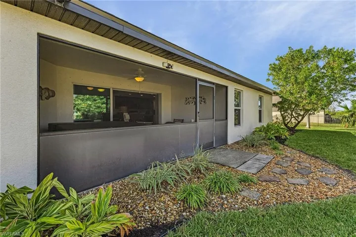 Entrance to property with a lawn and ceiling fan