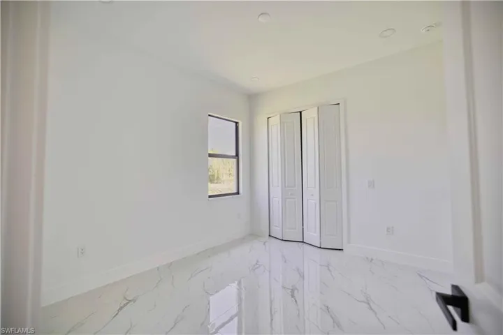 Bright interior space featuring white walls and marble-look tile flooring