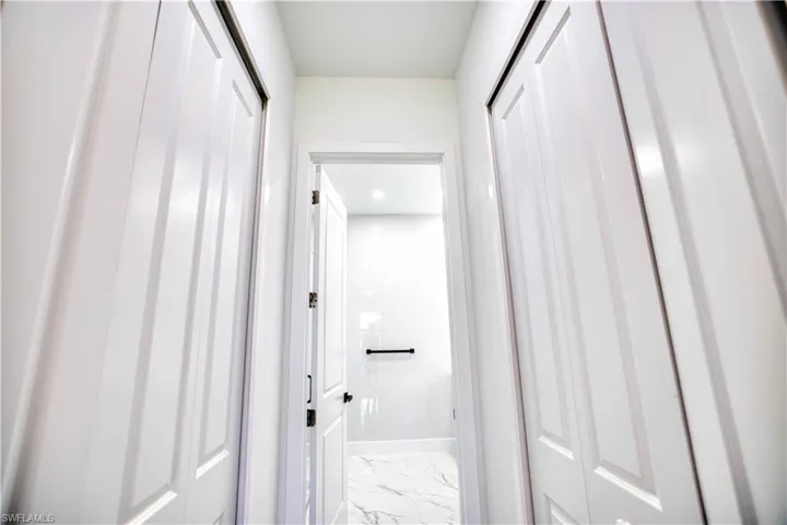 White paneled bifold closet doors framing a hallway entrance to a bathroom
