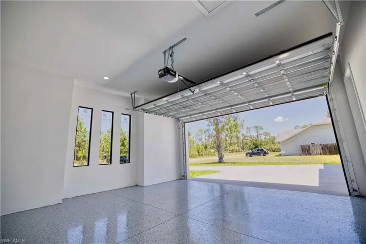 Spacious garage featuring a durable epoxy-coated floor, bright white walls, and a large overhead door