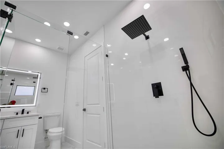 Modern bathroom featuring a frameless glass shower enclosure with matte black fixtures