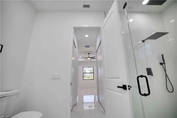 Walk-in shower featuring a glass enclosure and matte black rain showerhead, handheld shower, and fixtures