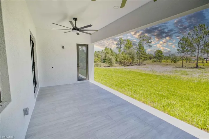 Expansive covered patio featuring light-toned tile flooring and a modern ceiling fan
