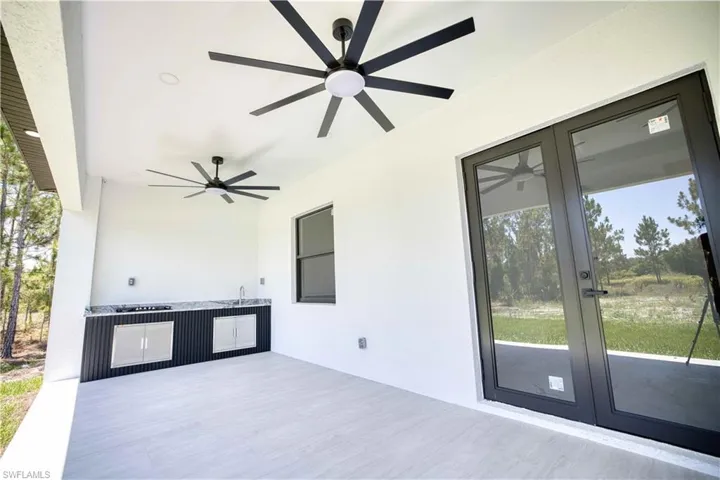 Covered patio featuring two black ceiling fans with integrated lighting
