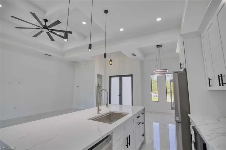 Kitchen island featuring an undermount sink, gooseneck faucet, and light-toned countertop