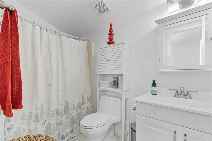 Bathroom with vanity, a textured ceiling, toilet, and walk in shower