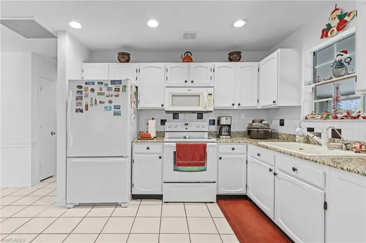 Kitchen with white cabinetry, sink, backsplash, white appliances, and light tile patterned floors