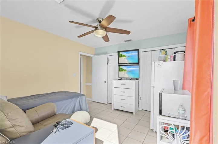 Bedroom featuring ceiling fan, a closet, light tile patterned floors, and white refrigerator