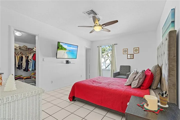 Tiled bedroom featuring a textured ceiling, a walk in closet, a closet, and ceiling fan
