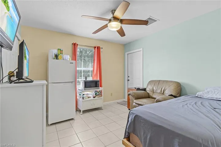 Tiled bedroom featuring white refrigerator and ceiling fan