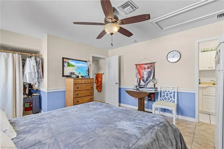 Tiled bedroom featuring ensuite bath and ceiling fan