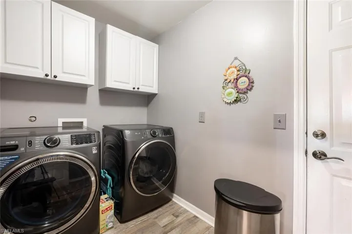Washroom featuring cabinets, washing machine and dryer, and light wood-type flooring