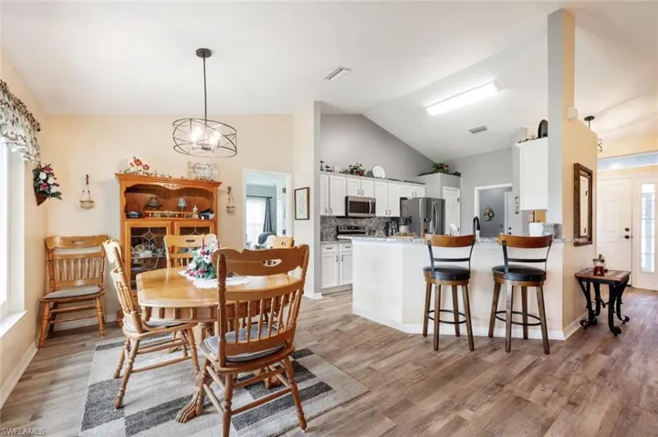 Dining room featuring light hardwood / wood-style flooring, a notable chandelier, and high vaulted ceiling