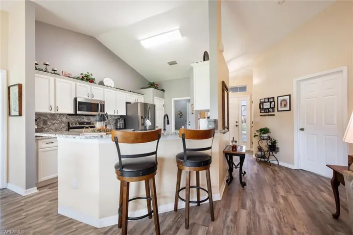 Kitchen featuring kitchen peninsula, stainless steel appliances, hardwood / wood-style flooring, and white cabinetry