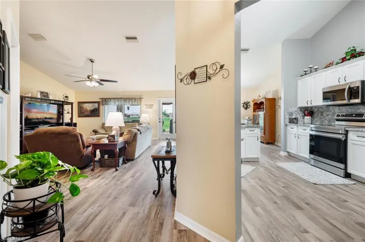 Kitchen featuring light hardwood / wood-style flooring, decorative backsplash, appliances with stainless steel finishes, ceiling fan, and white cabinets