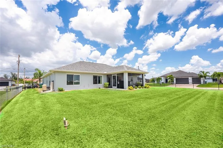 Rear view of property featuring a garage and a lawn