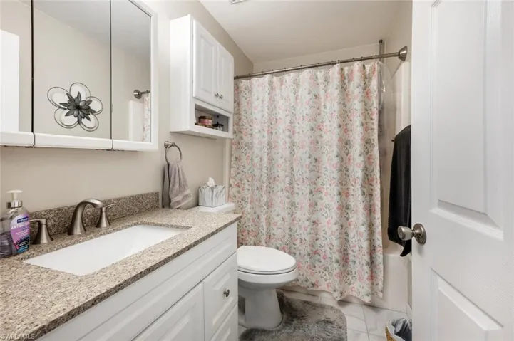 Bathroom with toilet, vanity, and tile patterned flooring