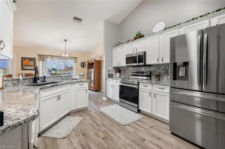 Kitchen featuring light hardwood / wood-style flooring, white cabinetry, backsplash, stainless steel appliances, and sink