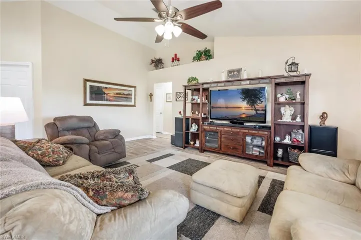 Living room featuring ceiling fan, light wood-type flooring, and high vaulted ceiling