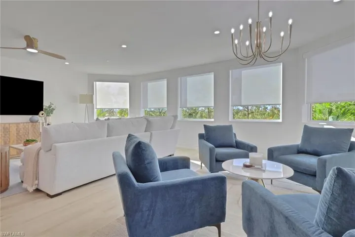 Living area featuring wood finished floors, healthy amount of natural light, recessed lighting, and a chandelier