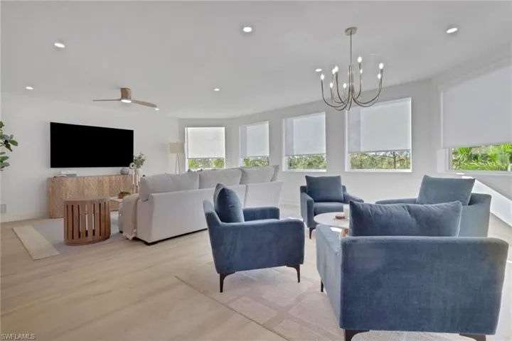 Living room featuring wood finished floors, recessed lighting, ceiling fan, and a chandelier