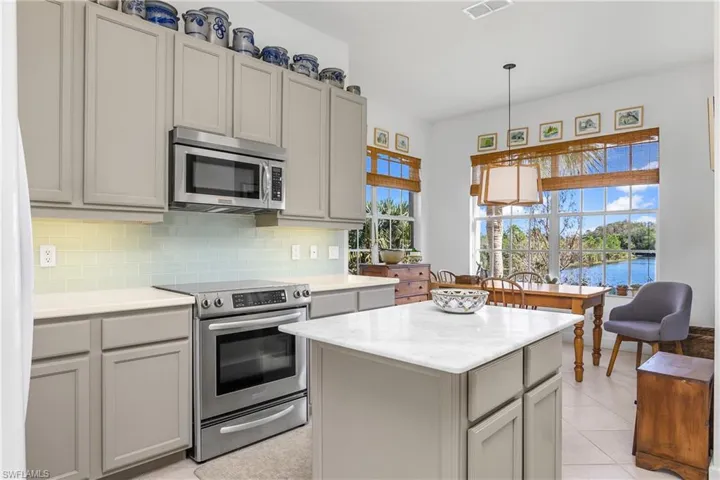 Center island, plenty of custom cabinetry space, stainless stove and microwave...breakfast nook beyond.