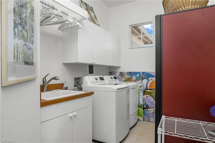 Large laundry room with tub, storage cabinetry and garment hanging space