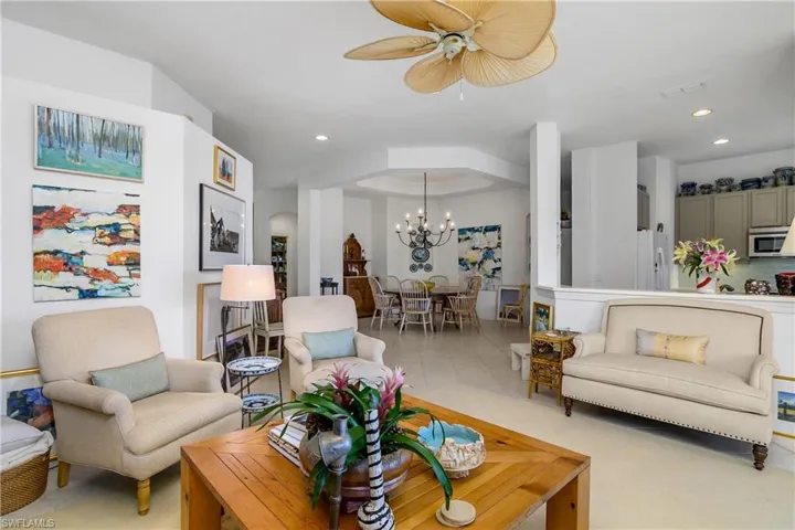 Living area, kitchen to right and dining area at center. Neutral color floor tile and interior walls.