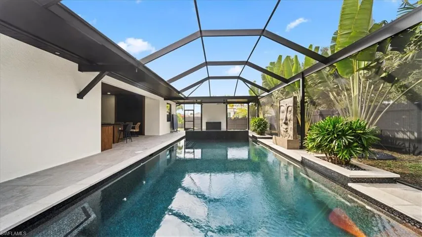 Outdoor pool featuring glass enclosure, a sunroom, and a patio