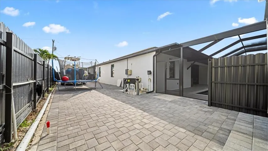 Fenced backyard featuring a trampoline, a sunroom, a lanai, and a patio