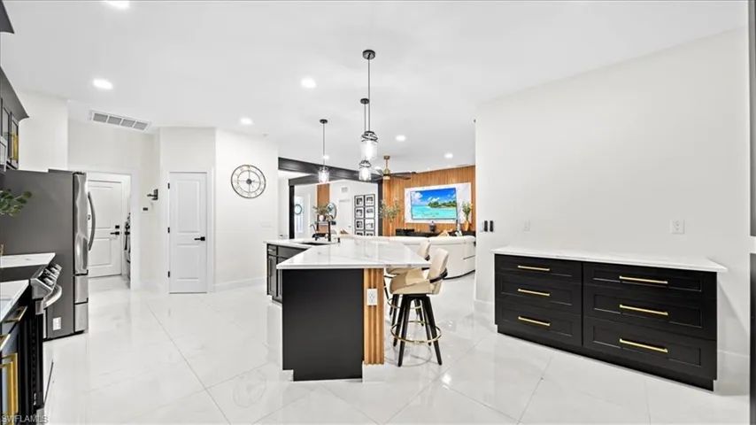 Kitchen featuring dark cabinetry, light stone counters, a large island, a kitchen breakfast bar, and open floor plan