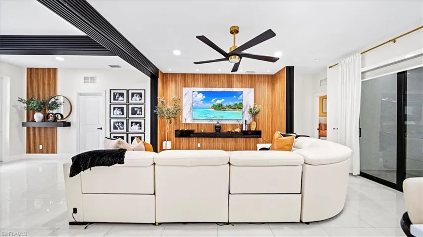 Living area with wood walls, an accent wall, ceiling fan, and recessed lighting
