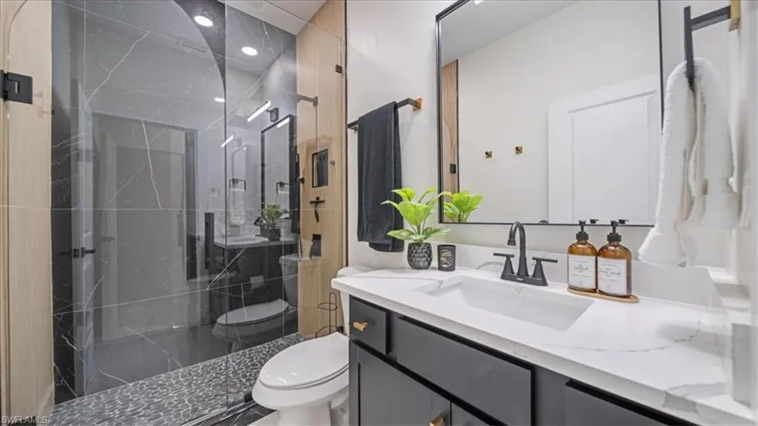 Full bath featuring vanity, a marble finish shower, and recessed lighting