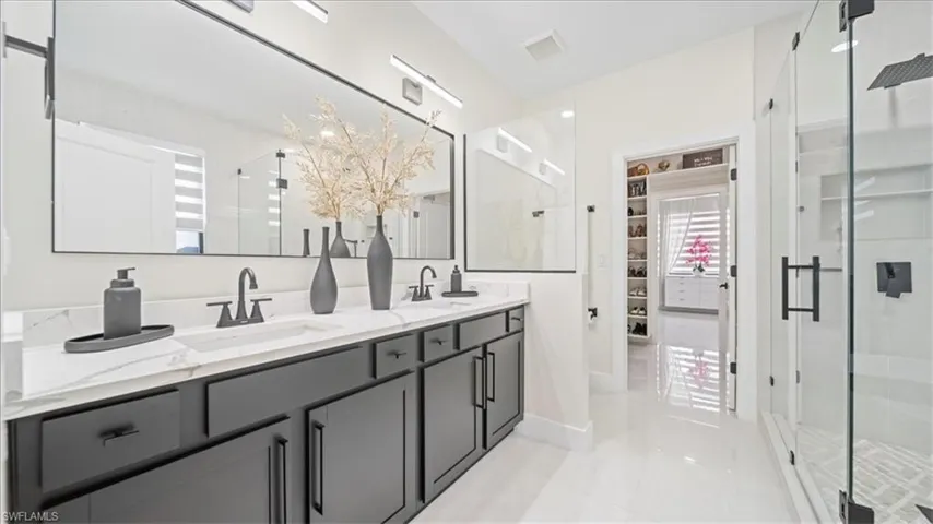 Bathroom featuring a shower stall and double vanity