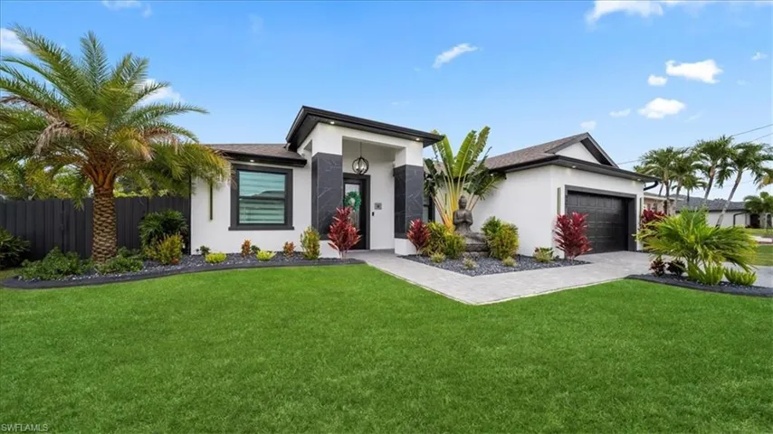 View of front facade featuring stucco siding, an attached garage, and driveway