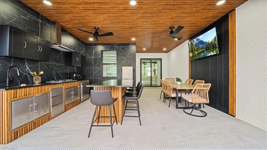 Kitchen featuring wood ceiling, recessed lighting, a breakfast bar area, a center island, and wall chimney range hood
