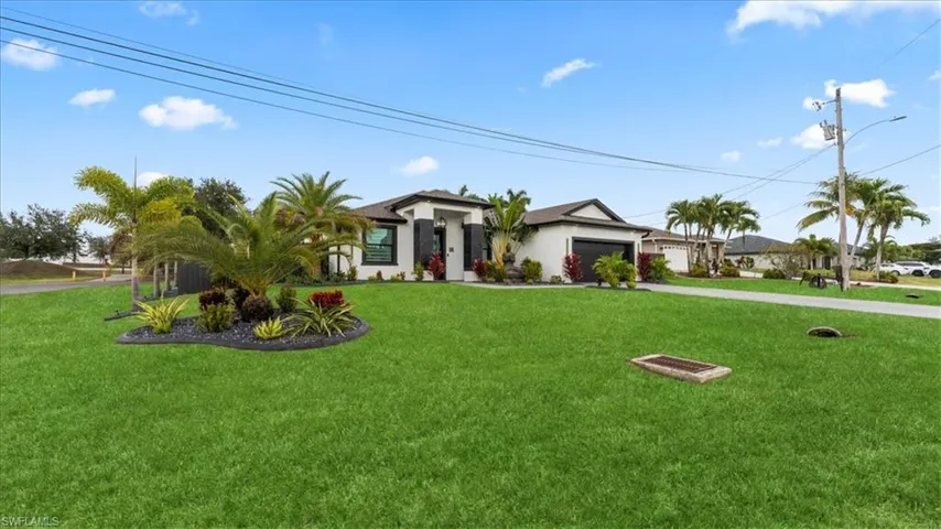 View of front of property featuring a front yard, a garage, driveway, and stucco siding