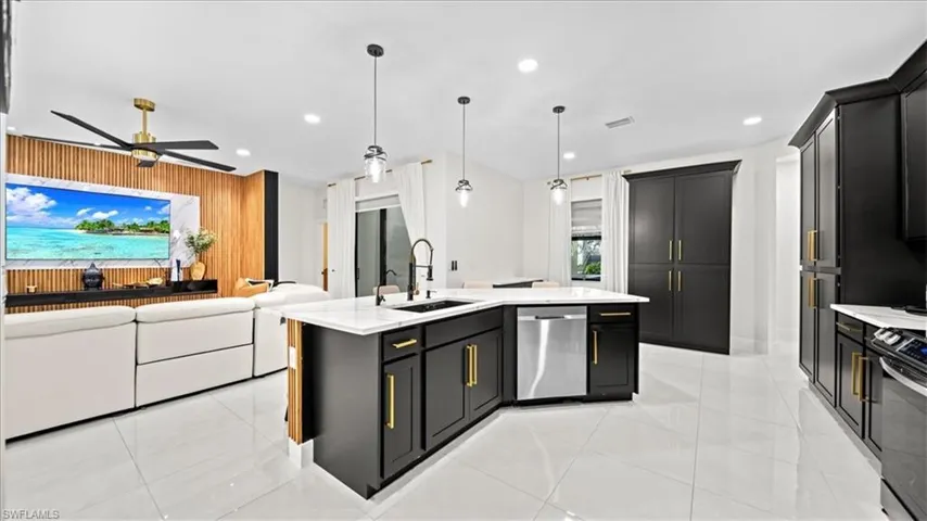 Kitchen with dark cabinets, open floor plan, pendant lighting, stainless steel dishwasher, and recessed lighting