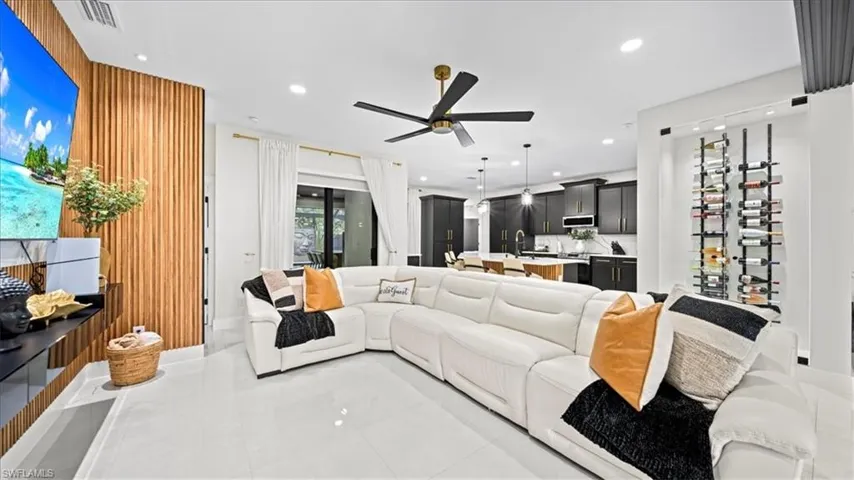 Living room featuring recessed lighting, wooden walls, light tile patterned floors, and ceiling fan