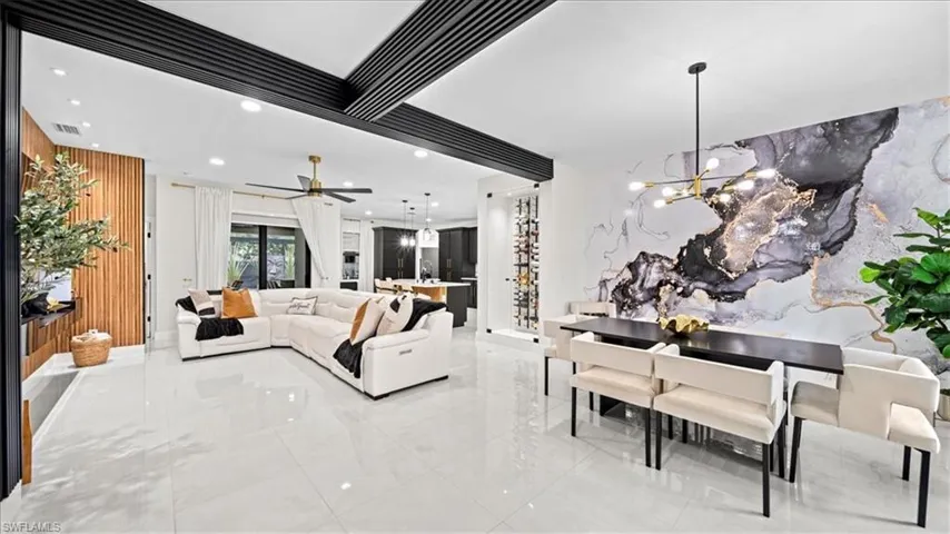 Living room featuring a chandelier, an accent wall, recessed lighting, a ceiling fan, and marble tiled flooring