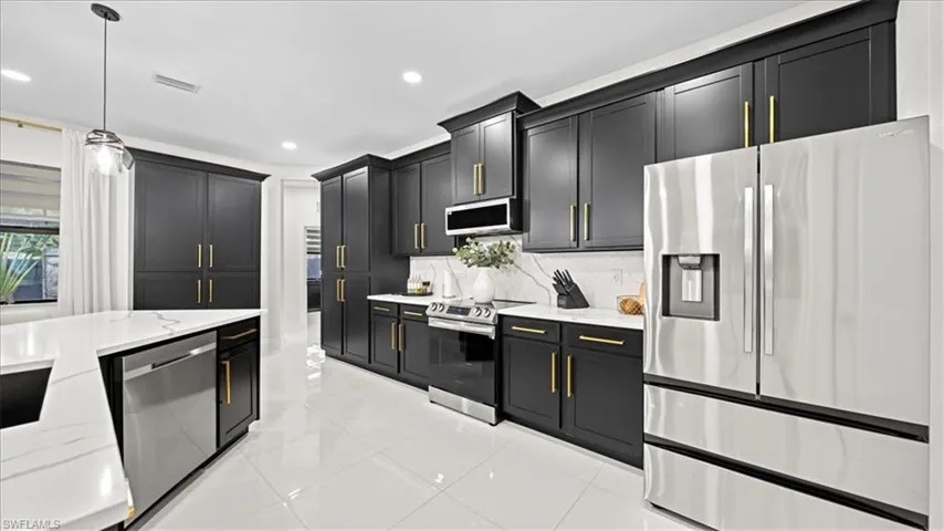 Kitchen with appliances with stainless steel finishes, dark cabinetry, and recessed lighting