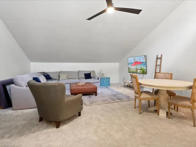 Living room with ceiling fan, light carpet, and vaulted ceiling