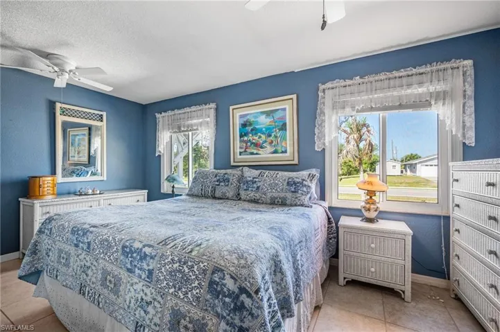 Spacious room featuring multiple windows with white trim, ceramic tile flooring, and a ceiling fan