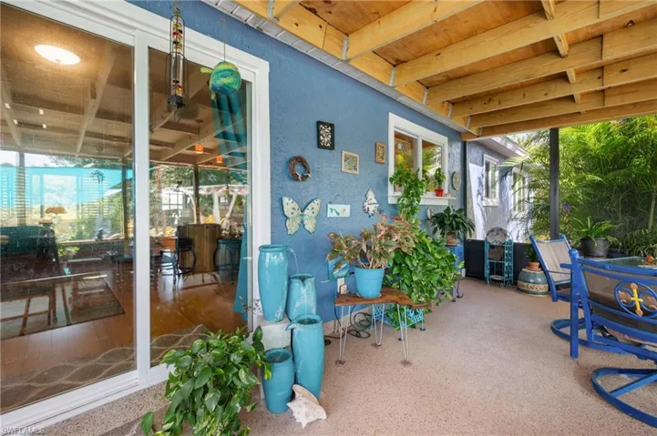 Covered patio featuring a textured concrete surface, exposed wood ceiling beams, a sliding glass door, and a painted exterior wall