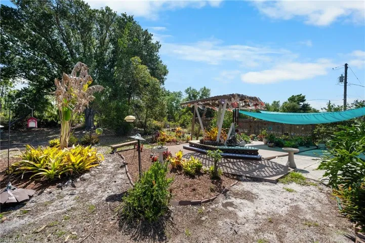 Expansive outdoor space featuring a concrete patio, a wooden pergola, and a vibrant shade sail