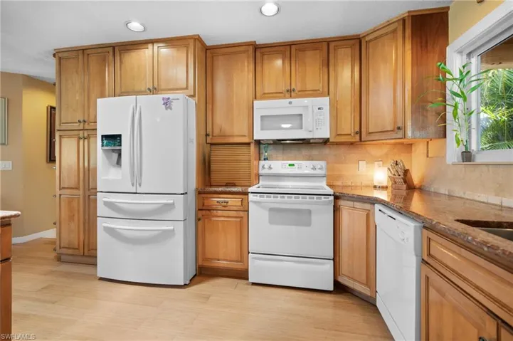 Kitchen featuring wood-finish cabinetry, light-toned wood-finish flooring, recessed lighting, white built-in microwave, and a white electric range