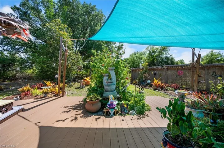 Expansive outdoor deck featuring wood-finish flooring and a partial blue shade canopy