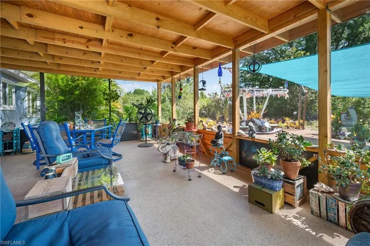 Expansive covered patio featuring a wood-beam ceiling, concrete flooring, and an open-air design