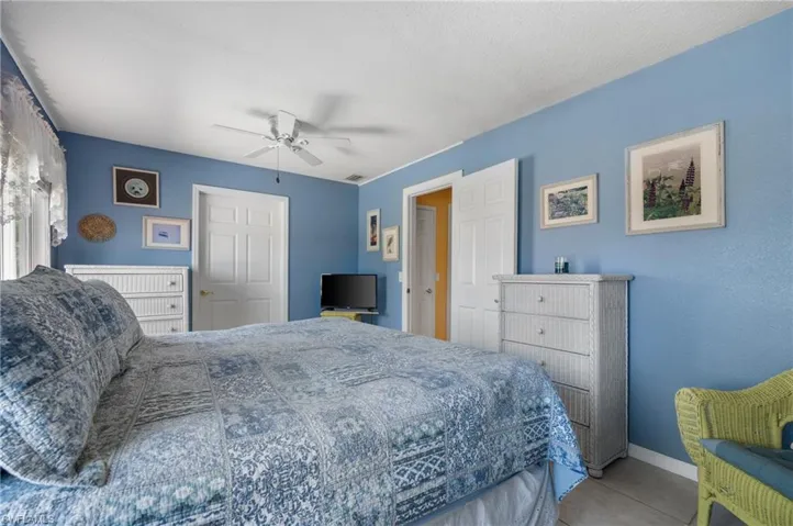 Bedroom featuring light blue walls and a white ceiling fan with integrated lighting