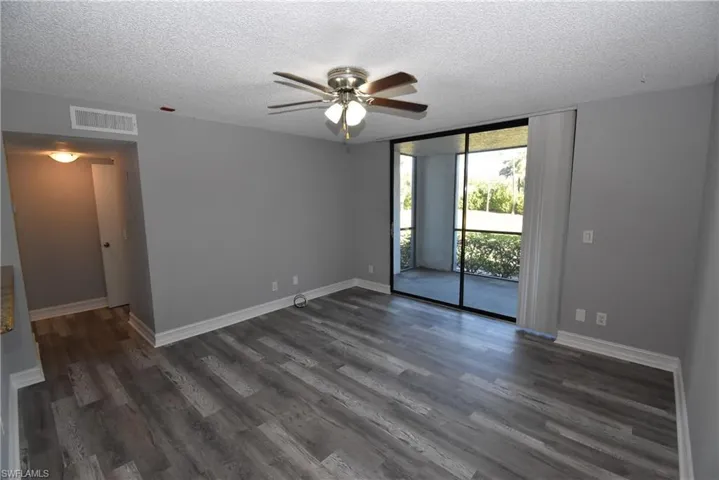 Spare room featuring floor to ceiling windows, ceiling fan, a textured ceiling, and dark wood-style floors